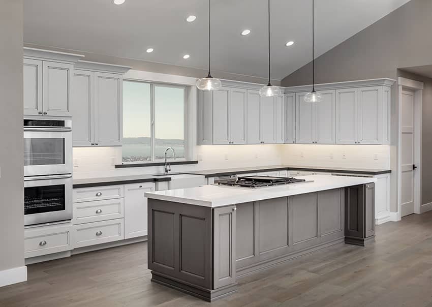 L shaped kitchen layout with island and white cabinets and two types of countertops