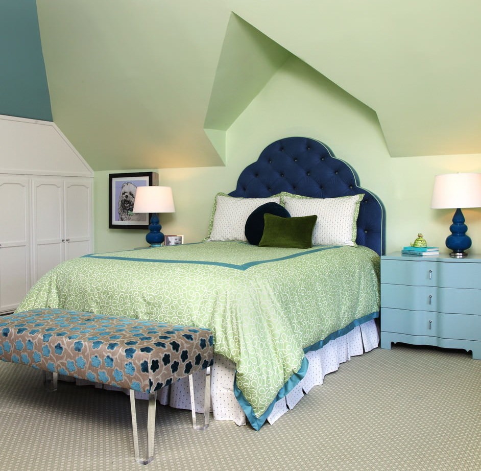 Синее изголовье кровати в комнате с зелеными стенами