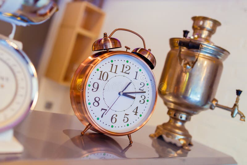 Antique clocks stand on a wooden table against the background of an old samovar.  royalty free stock image