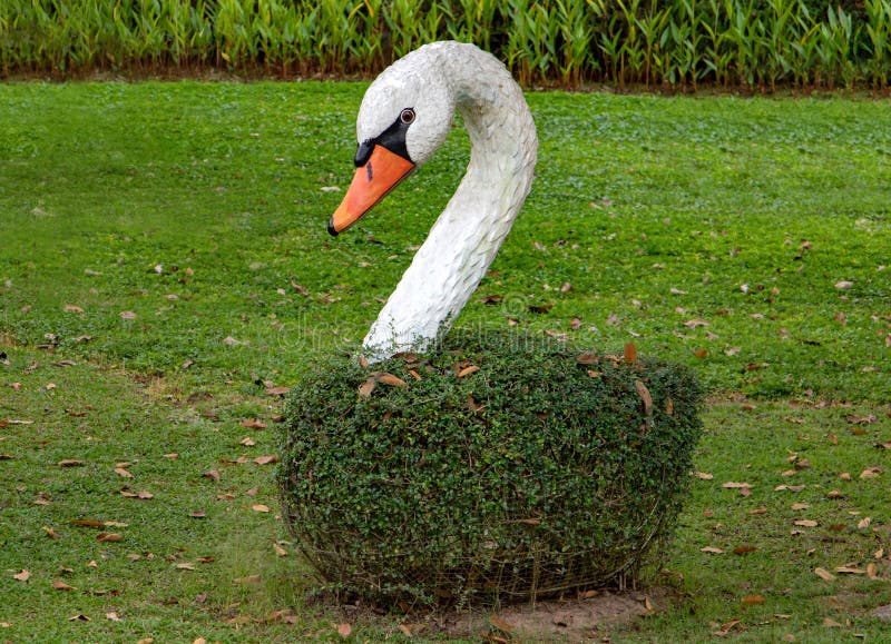 Artificial imitation of swan as romantic decoration of the garden. Model of beautiful white bird in park stock photography