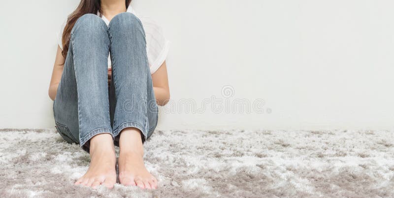 Asian woman sit on gray carpet floor with white cement textured background at the corner of house with copy space. Closeup woman sit on gray carpet floor with royalty free stock photos