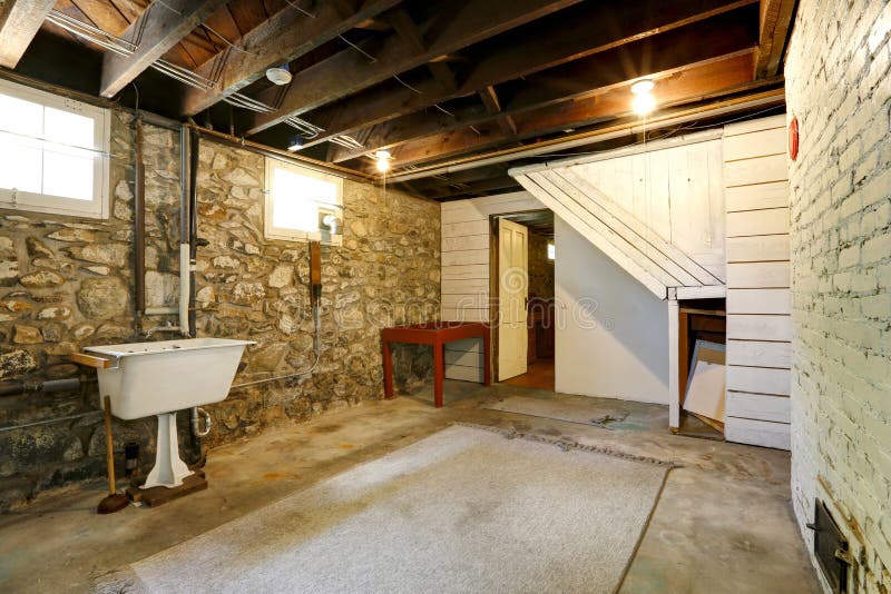 Basement room with stone trim walls. Basement empty room interior with stone wall trim and brick wall with fireplace. Room with old sink royalty free stock images