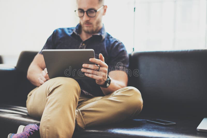 Bearded manager working tablet device modern Interior Design Loft Building.Man relax Vintage sofa use contemporary. Bearded manager work tablet device modern royalty free stock image