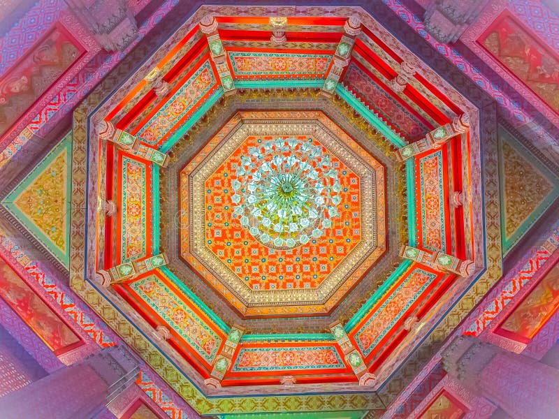 Beautiful chandelier lamp is hanging on the decorated ceiling in. The Buddhist church, Thailand. Colorful pattern of ceiling with decorative chandelier lamp stock image
