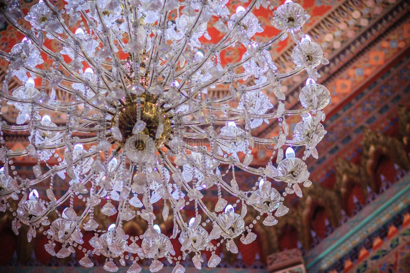 Beautiful chandelier lamp is hanging on the decorated ceiling in. The Buddhist church, Thailand. Colorful pattern of ceiling with decorative chandelier lamp stock photos