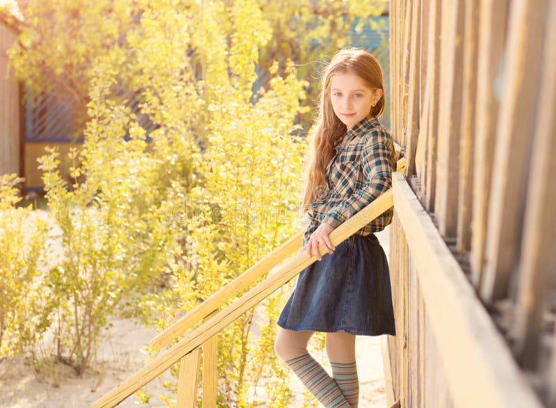 Beautiful little girl on stairs of wooden house. On sunny day stock images