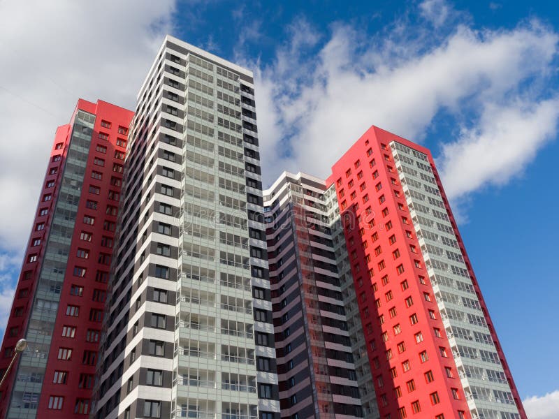 Beautiful red-black-white facades of new high-rise apartment buildings in the blue sky. Bottom view. The theme of an emerging housing market under construction stock photo