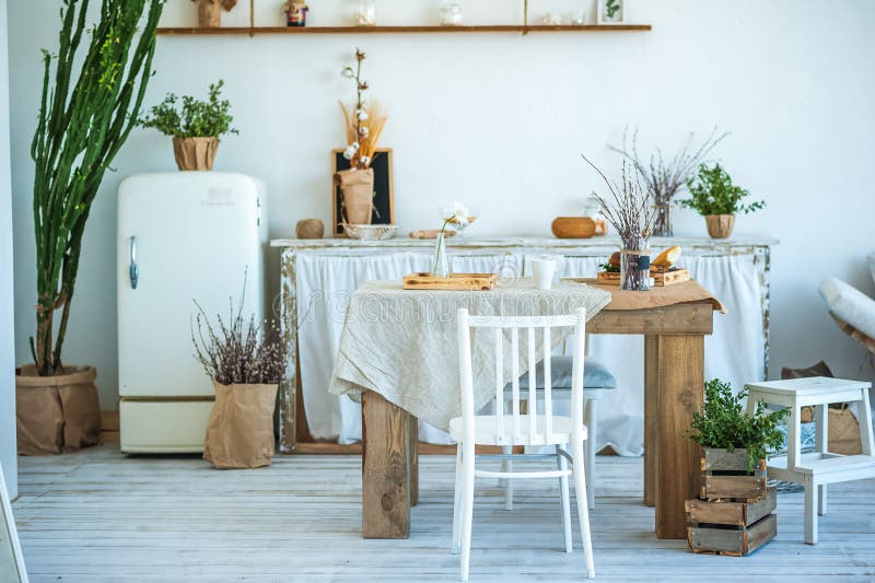 Beautiful spring photo of kitchen interior in light textured colors. Kitchen, living room with beige sofa sofa, old retro white fr. Idge, rustic table, large stock images