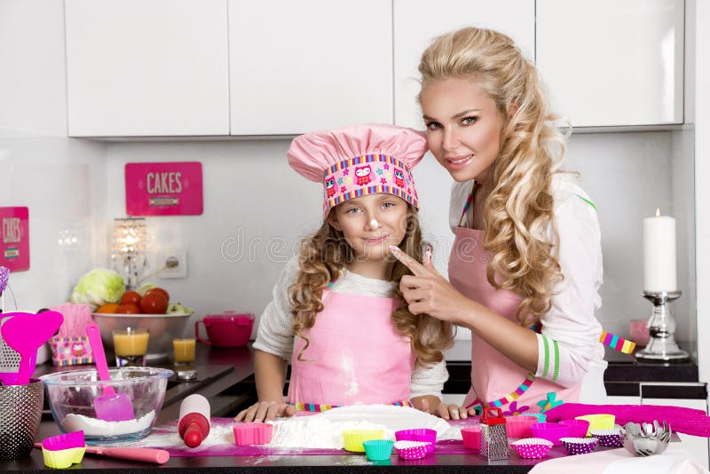 Beautiful stunning woman mother and daughter in aprons kitchen cooking in the kitchen cookies stock image