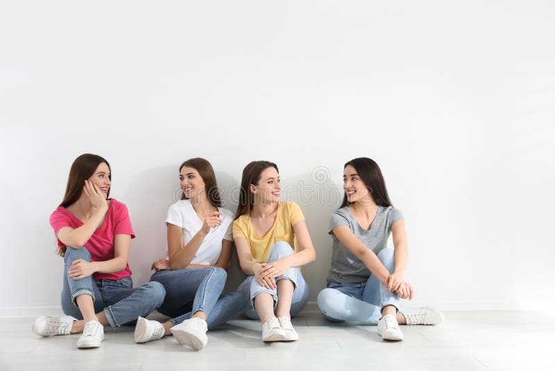 Beautiful young ladies in jeans and colorful t-shirts near white wall. Woman`s Day royalty free stock image