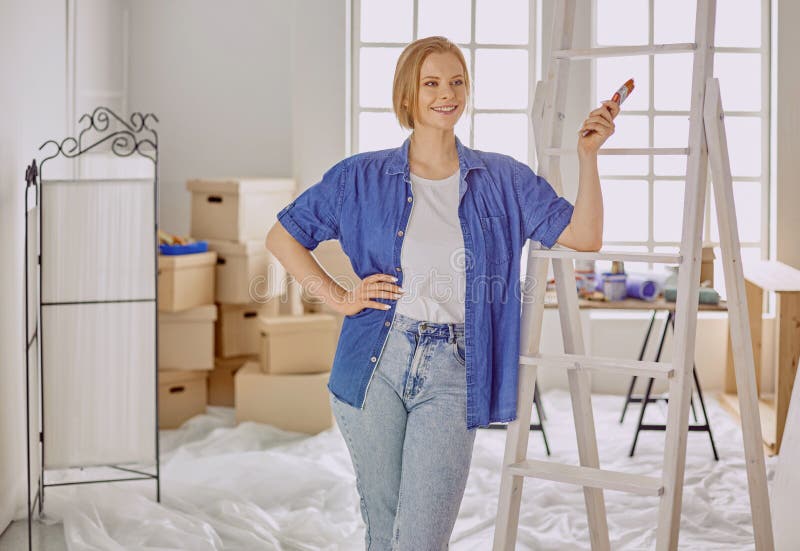 Beautiful young woman on a white wooden stepladder. Ready to repair the room. Women housework concept.  royalty free stock photography