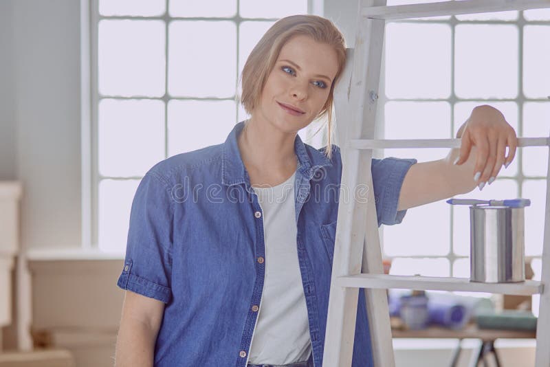 Beautiful young woman on a white wooden stepladder. Ready to repair the room. Women housework concept.  royalty free stock image