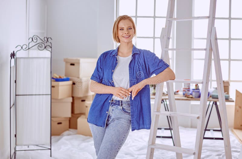 Beautiful young woman on a white wooden stepladder. Ready to repair the room. Women housework concept.  royalty free stock photo