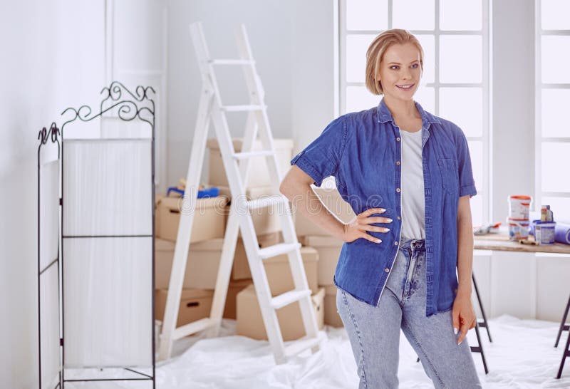 Beautiful young woman on a white wooden stepladder. Ready to repair the room. Women housework concept.  royalty free stock photos