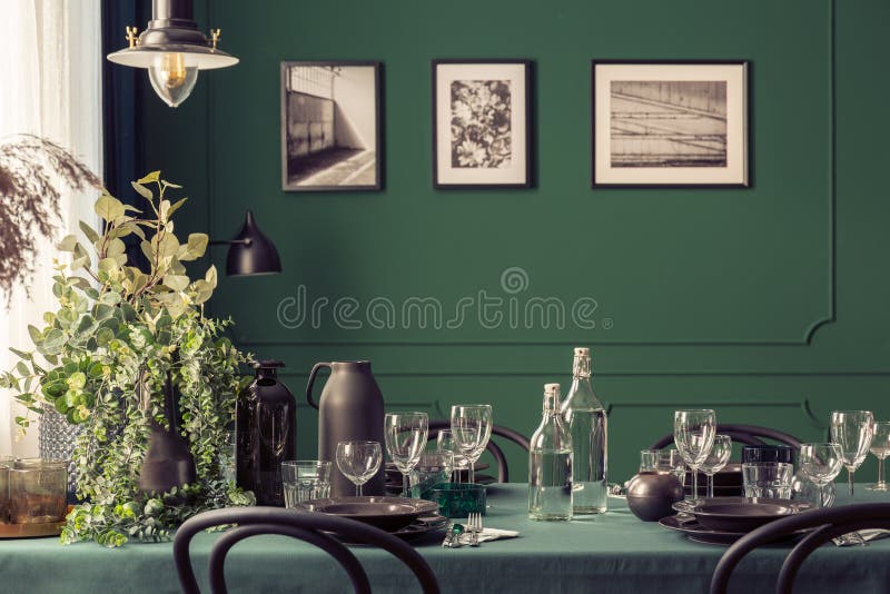 Black and green design of elegant dining table in fashionable interior with gallery of posters on the wall royalty free stock image