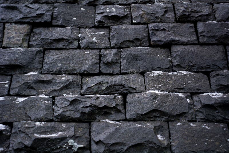 Black stone wall background texture. Black stone wall with snowe winternlair digital texture wall brick build brickwork color backdrop massive structure stock photography