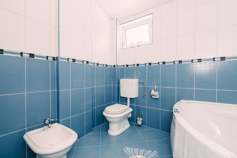 Bellagio, Italy - 07 june 2020: A blue bathroom with a toilet, sink, bathtub and a window open for ventilation. A blue bathroom with a toilet, sink, bathtub and stock images