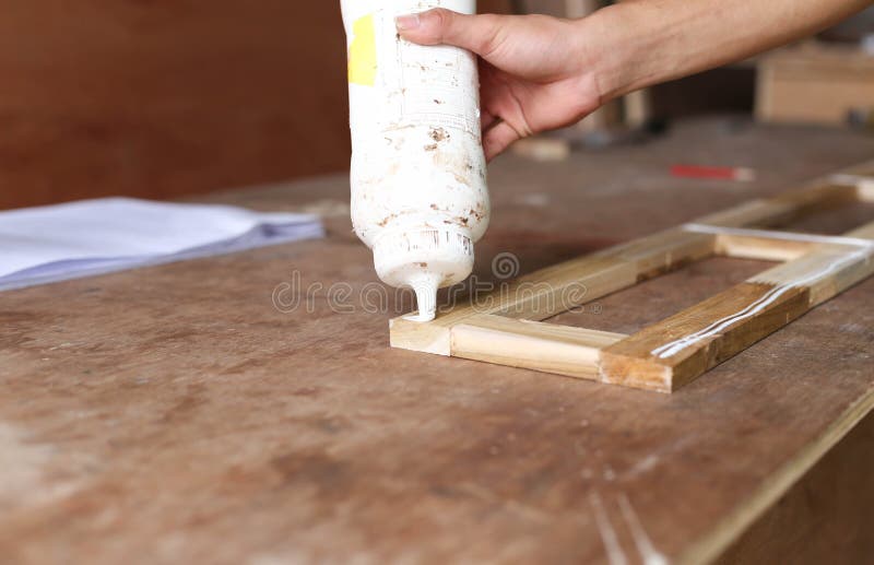 Carpenter putting glue on a piece of wood stock photo