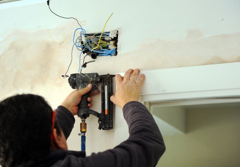 Carpenter using a compressed air nailer to insert nails in the assembly of a sliding door royalty free stock photography