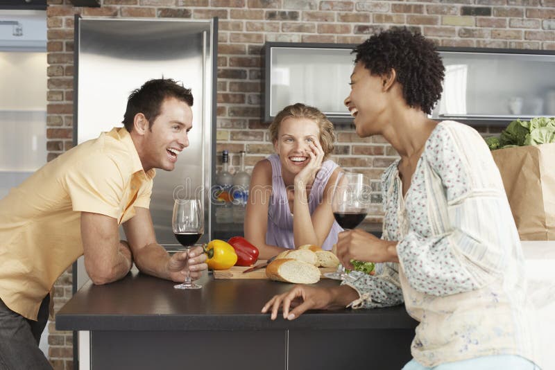 Cheerful Friends At Kitchen Counter. Cheerful multiethnic friends enjoying drinks at kitchen counter stock images
