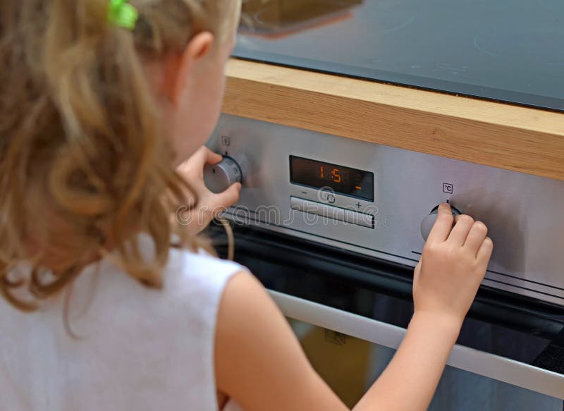 Child playing with electric oven. Dangerous situation in the kitchen. Child playing with electric oven royalty free stock photo
