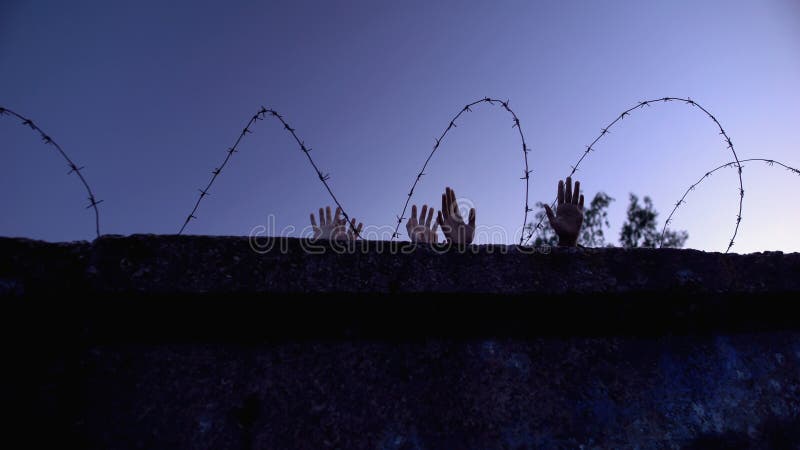 Children and adult hands behind barbed wire, forced settlements, refugee camp royalty free stock photos
