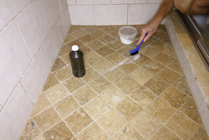 Cleaning Grout with Natural Ingredients. Adult male hand with a small blue and black brush cleaning floor grout in a shower. White male cleaning shower grout royalty free stock photography