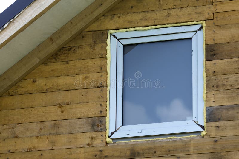 Close-up detail of new narrow plastic vinyl window installed in. House wall of brown natural wooden planks and boards. Real estate property, comfortable cottage royalty free stock image