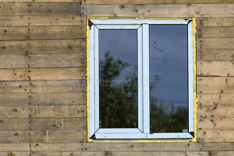 Close-up detail of new narrow plastic vinyl window installed in. House wall of brown natural wooden planks and boards. Real estate property, comfortable cottage royalty free stock photography