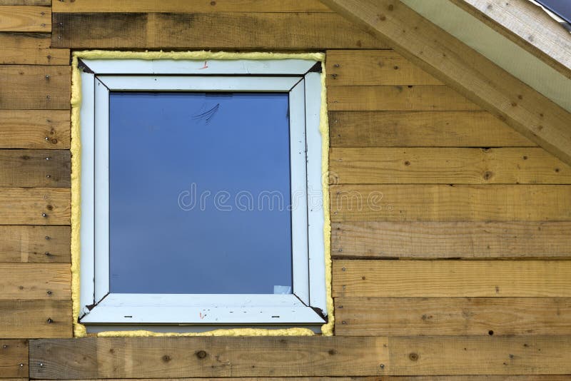 Close-up detail of new narrow plastic vinyl window installed in. House wall of brown natural wooden planks and boards. Real estate property, comfortable cottage royalty free stock image