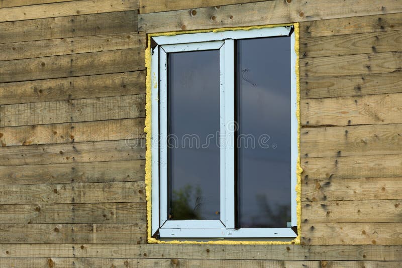 Close-up detail of new narrow plastic vinyl window installed in. House wall of brown natural wooden planks and boards. Real estate property, comfortable cottage royalty free stock photos