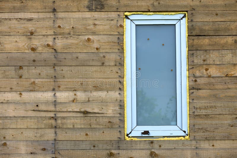 Close-up detail of new narrow plastic vinyl window installed in house wall of natural wooden planks. Close-up detail of new narrow plastic vinyl window stock images