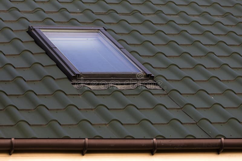 Close-up detail of new small attic plastic window installed in d. Ark green shingled house roof background. Professionally done building and construction work stock images