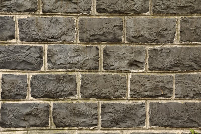 Black natural stone wall. Close up an details of a black natural stone wall with white lines stock photo