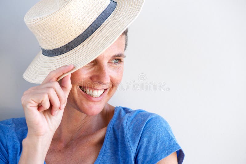 Close up beautiful mature woman smiling with hat against white wall royalty free stock image