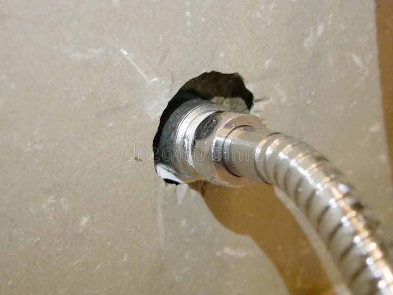 Rinsing spray hose connected to the water pipe, through a metalic joint with female - male thread. Close up of the rinsing spray hose connected to the water pipe royalty free stock photos