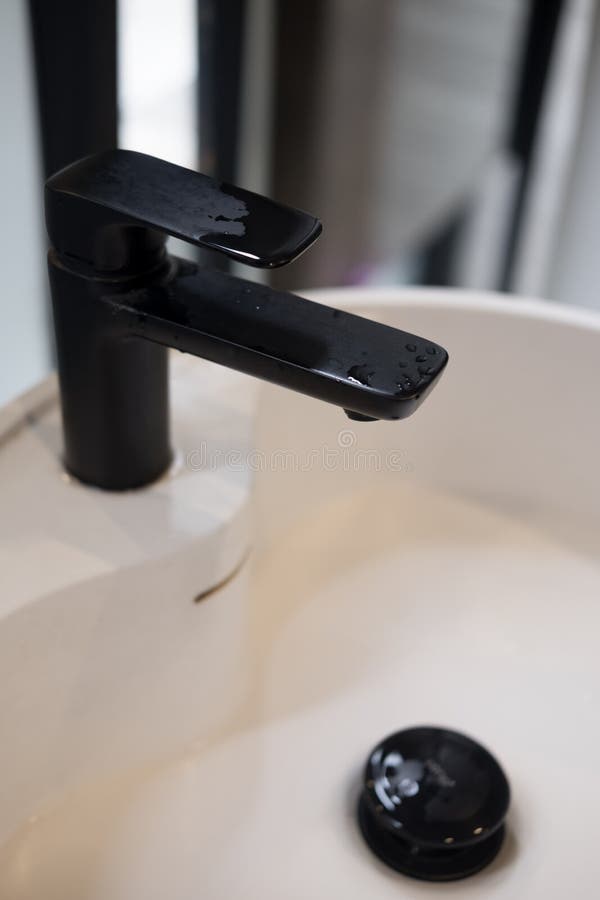 Close up on water falling from modern black tap stock photos