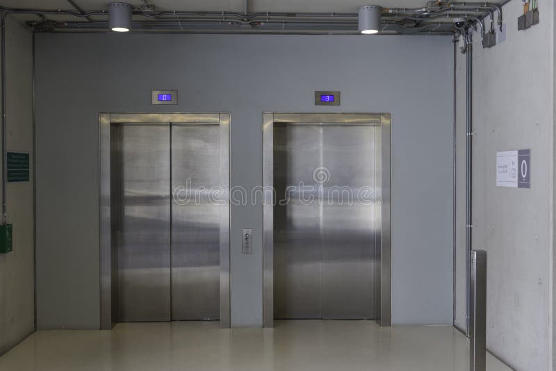 Closed elevators with buttons in corridor with concrete walls. stock photo