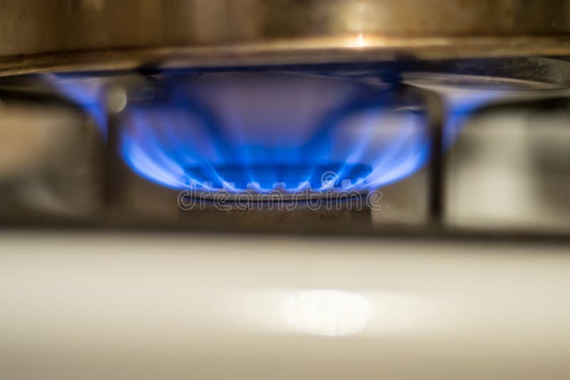 Closeup of a Home Gas Stove Burning. Blue flames as it heats up a silver pan royalty free stock image