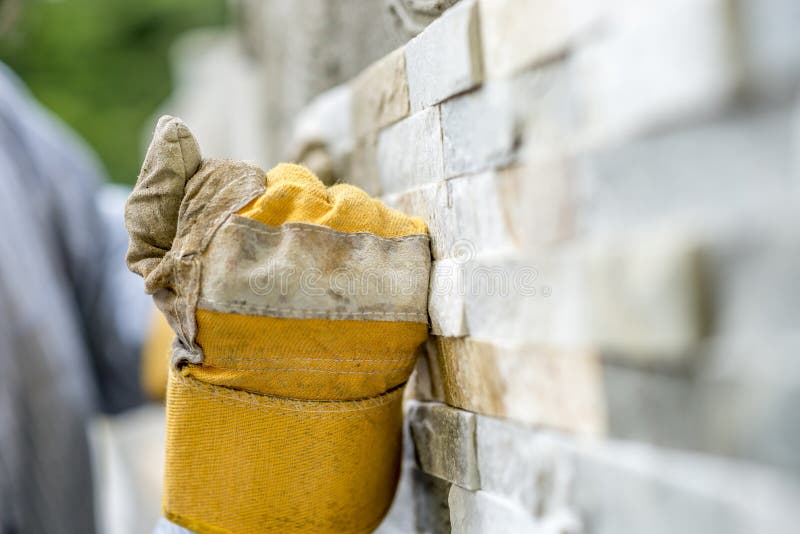 Closeup of manual worker in protection gloves tiling a wall wit stock image