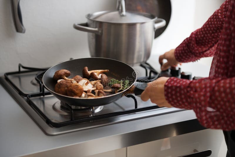 Closeup on young housewife putting pan on stove. In kitchen stock photo