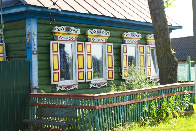Colorful windows with carved platbands on the decorated facade of the wooden house. Belarus stock photo