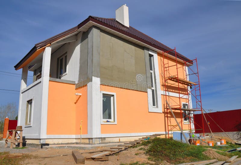 Construction or repair of the rural house with balcon, eaves, windows, chimney, roofing, fixing facade, insulation and painting. Construction or repair of the stock photo
