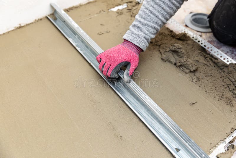Construction worker aligns concrete screed floor. With metal rail royalty free stock photos