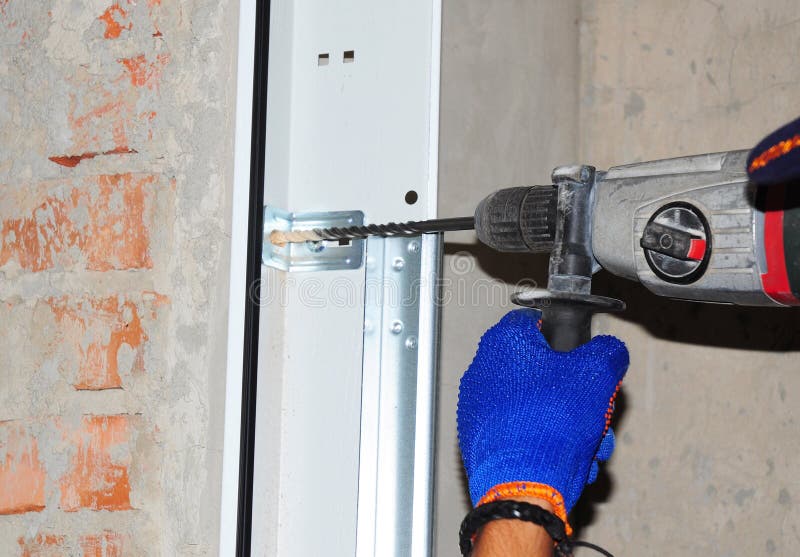 Contractor Installing Garage Door. Repairman use automatic screwdriver to drill the wall for garage door installation. Repairman use automatic screwdriver to stock photo