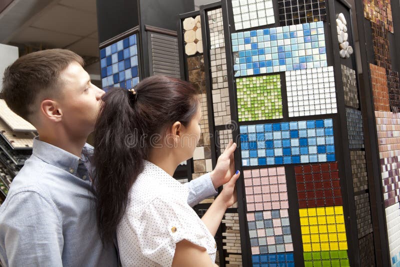 Couple pointing at ceramic mosaic tile for bathroom wall in store royalty free stock photo