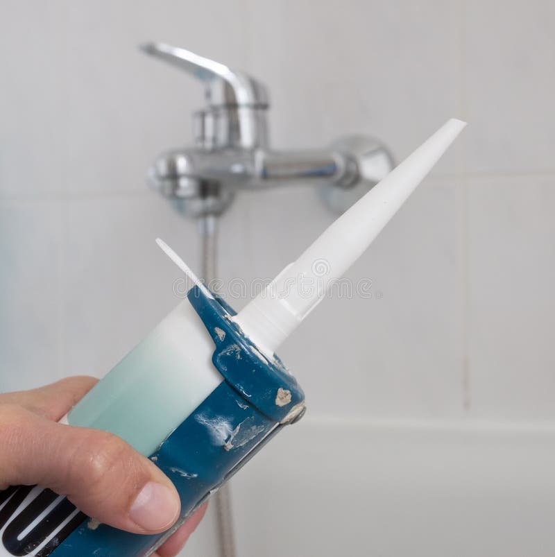 Silicone seal in the bathroom. Detail of a hand with a silicone gun and a bath in the background stock photos