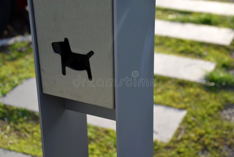 Detail of placement of dogs excrement bags in a metal post symbol dog  pedal road made of concrete tiles and chipped granite tiles. Detail of placement of dogs stock photography