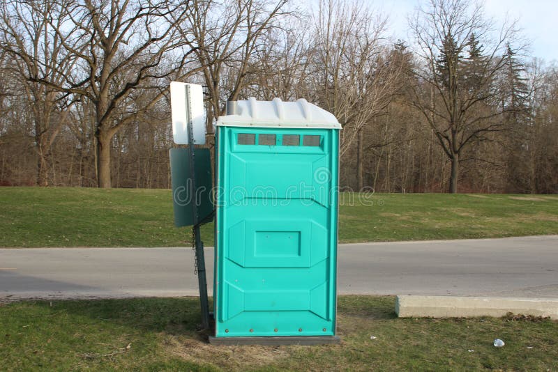 A Dirty, Blue Portable Toilet in a Park, nasty looking place to go to the bathroom. A Dirty, Blue Portable Toilet in a Park, with Scraps of Toilet paper royalty free stock photography