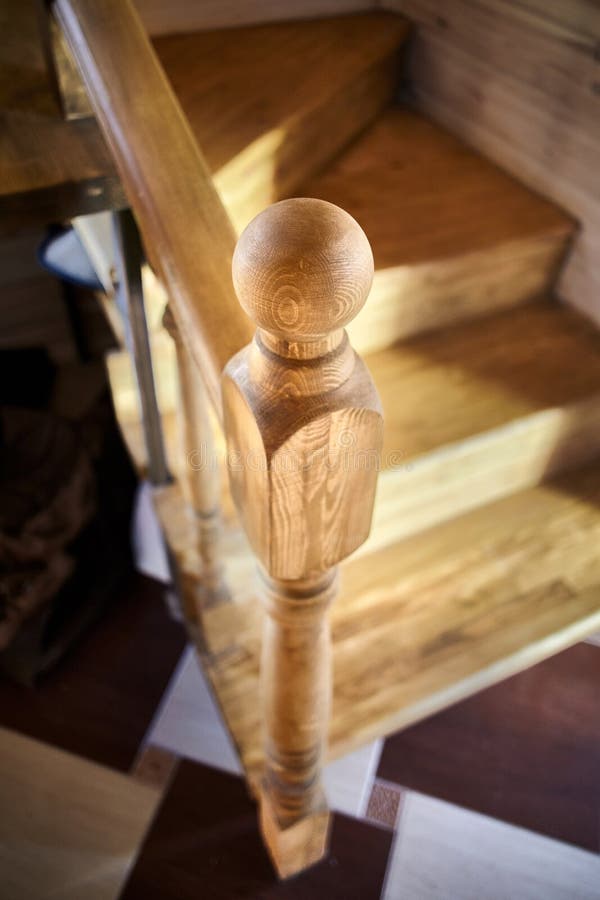 Elements of wood stairs. Round balusters inside cosiness wooden eco room close-up over shiny tiled floor. Background royalty free stock images